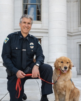 Golden Retriever Frost and his handlers an MPD officer sit in front of the Wisconsin State Capitol.