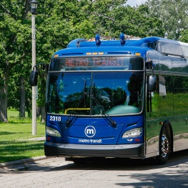 Metro Transit articulated bus traveling along a roadway beside a park.